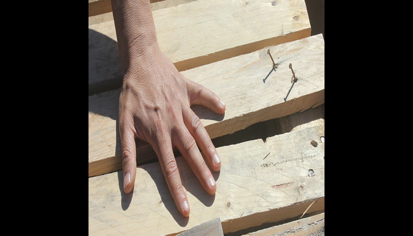 Närbild på en hand på några byggbräder.