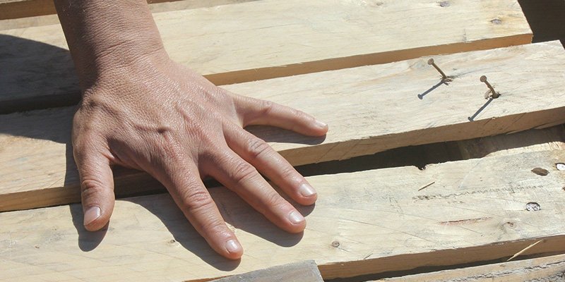 Närbild på en hand på några byggbräder.
