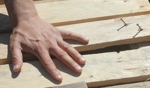 Närbild på en hand på några byggbräder.