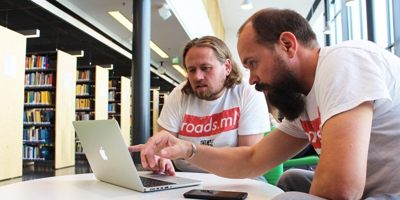 Antti Mattila och Jussi-Pekka Martikainen tittar på en bärbar dator i ett ljust bibliotek.