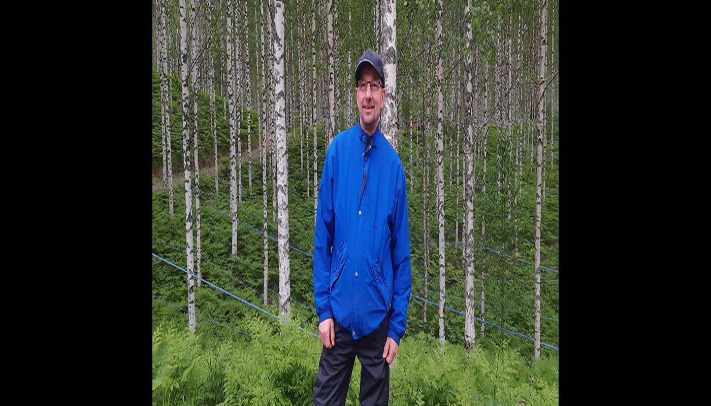 Kauko Kärkkäinen står framför en björkskog.