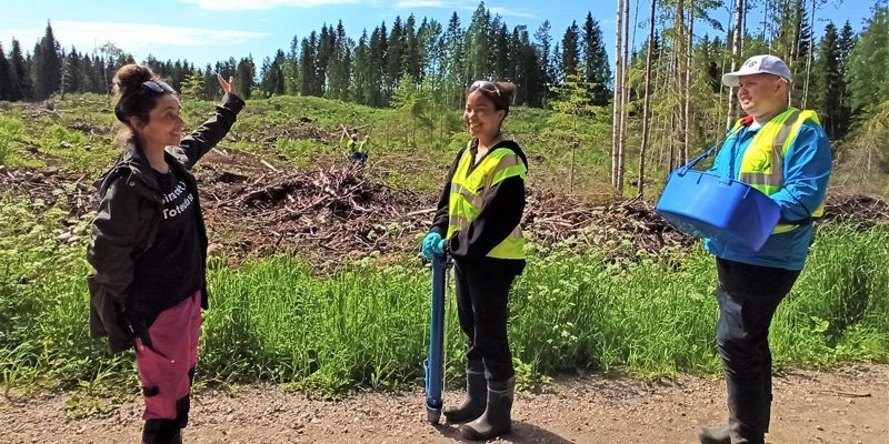 En kvinna förevisar ett planteringsområde för ett par ungdomar.