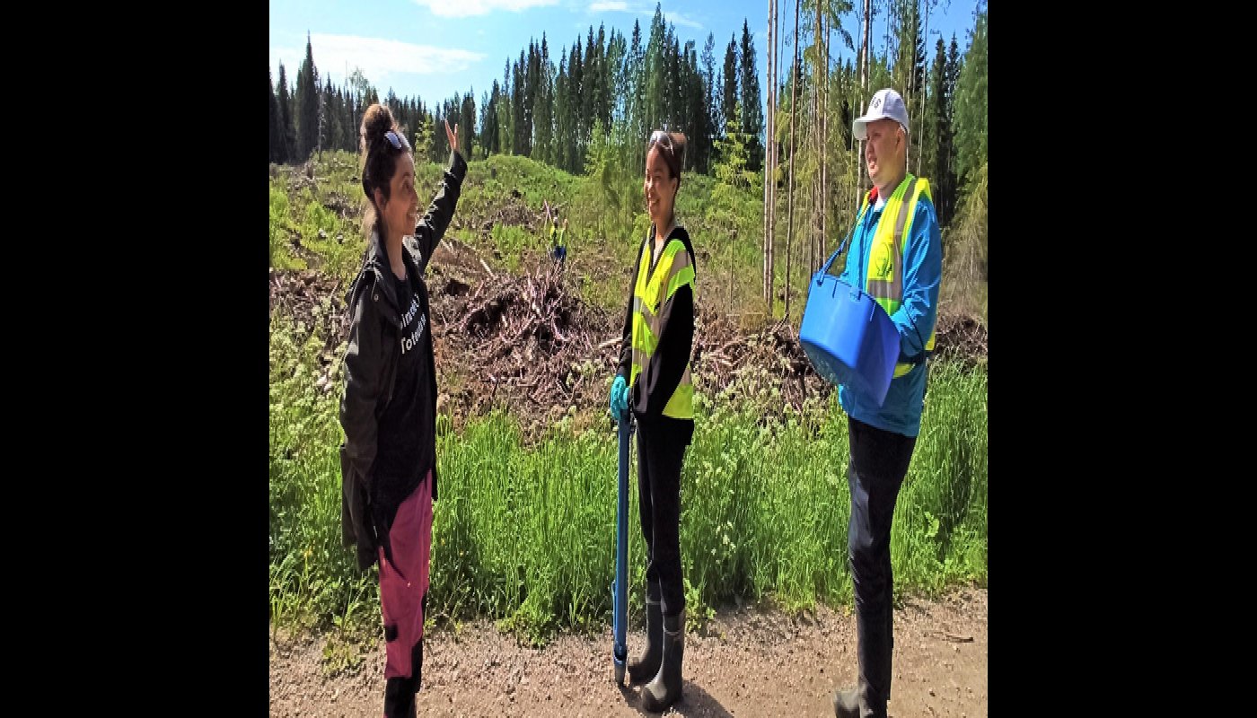 En kvinna förevisar ett planteringsområde för ett par ungdomar.