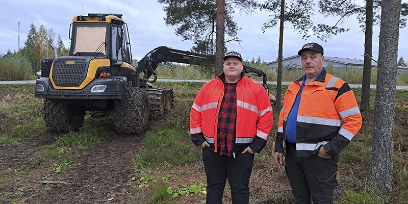 Jere och Jorma Hirsimäki står framför en skogsmaskin, vända mot kameran.