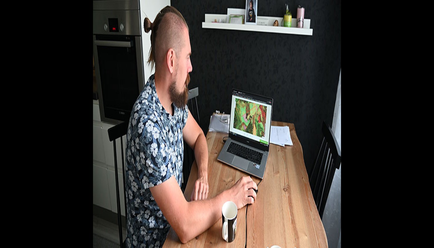 Tuomas Vakkila sitter vid köksbordet och tittar i tjänsten MinSkog.fi på en dator.
