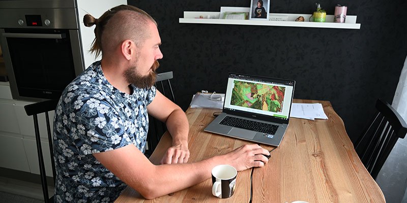 Tuomas Vakkila sitter vid köksbordet och tittar i tjänsten MinSkog.fi på en dator.
