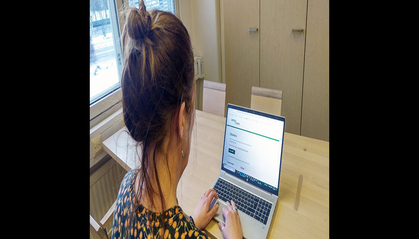 En kvinna sitter och tittar på en datorskärm med skatteförvaltningens tjänst öppen på skärmen.