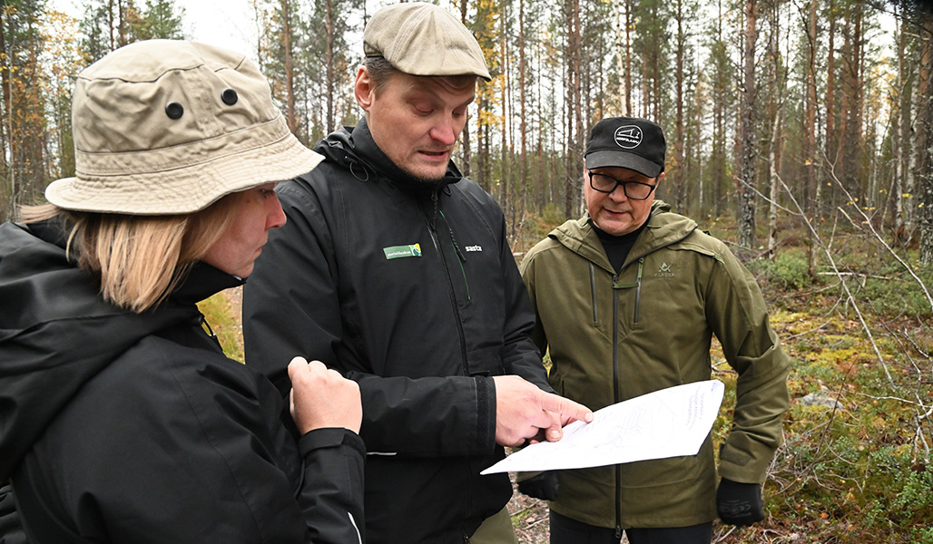 Riikka Salomaa, Ville Koukkari och Heikki Mosorin tittar på en karta tillsammans.