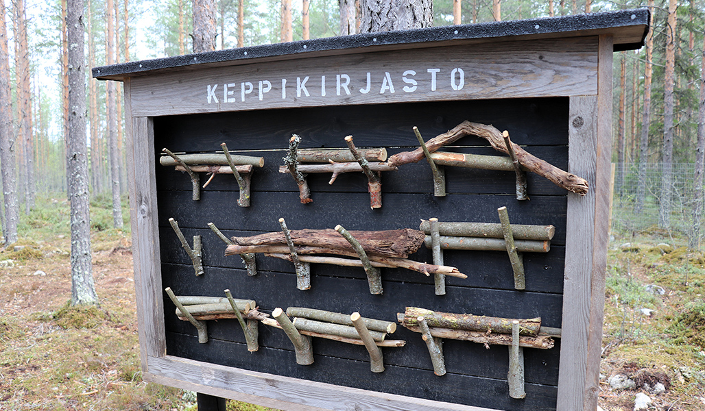 I skogen finns en skylt med texten "keppikirjasto” (käppbibliotek). I käppbiblioteket finns käppar som man kan kasta till hundarna.