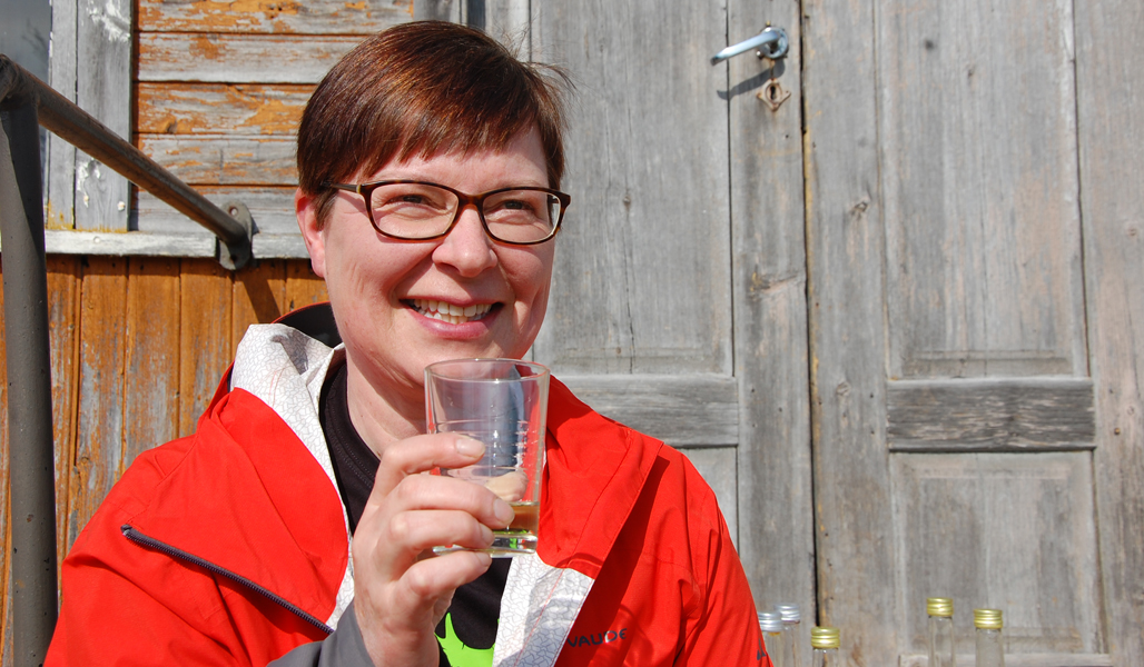 Tiina Aittolampi håller i ett glas med björksav.