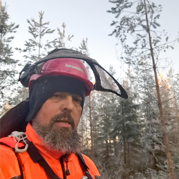 Juhani Toivakka har fotograferat sig själv i skogsarbetarhjälm i skogen på vintern.