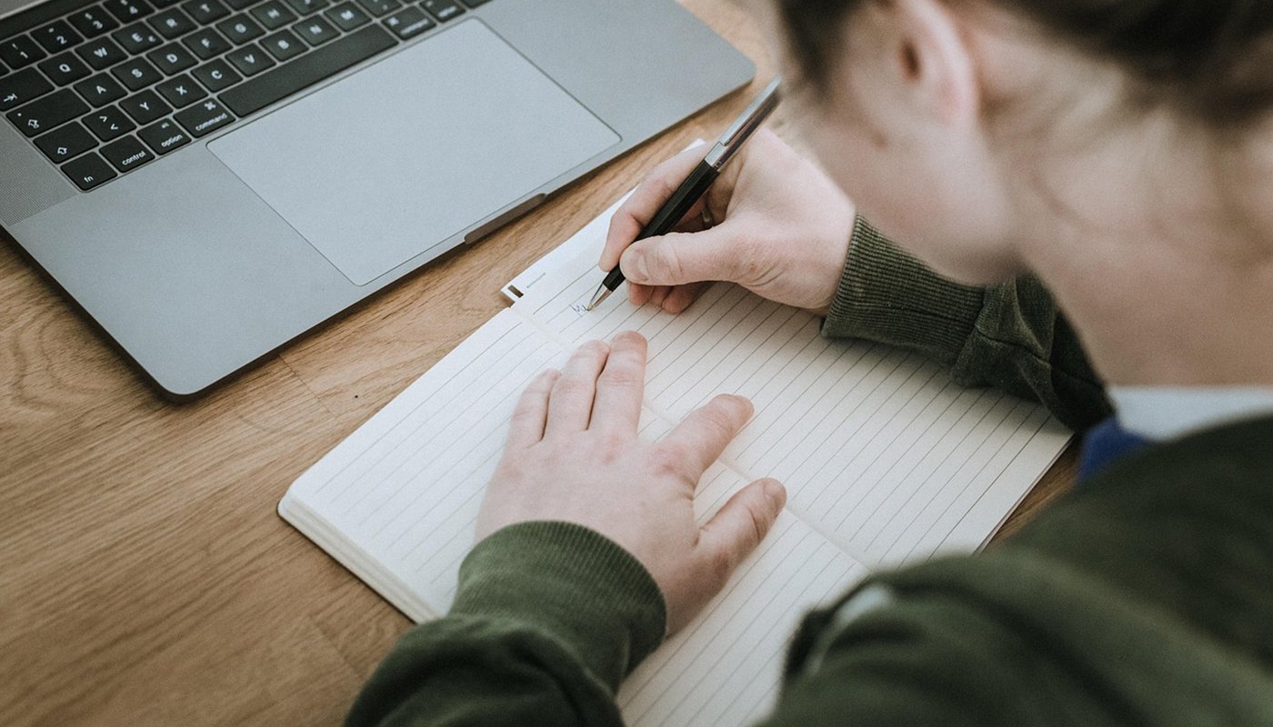 En person skriver anteckningar på ett papper.