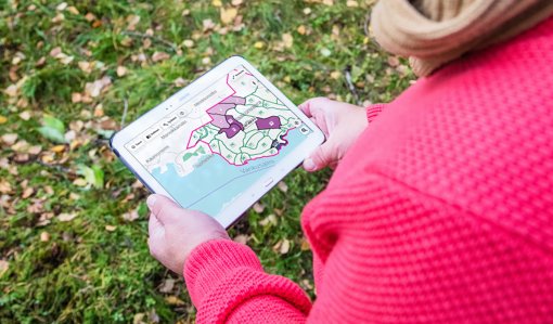 En person tittar på Metsään.fi‑tjänstens karta på en surfplatta.