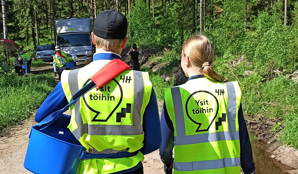 Två ungdomar står på en skogsväg med ryggen mot kameran.