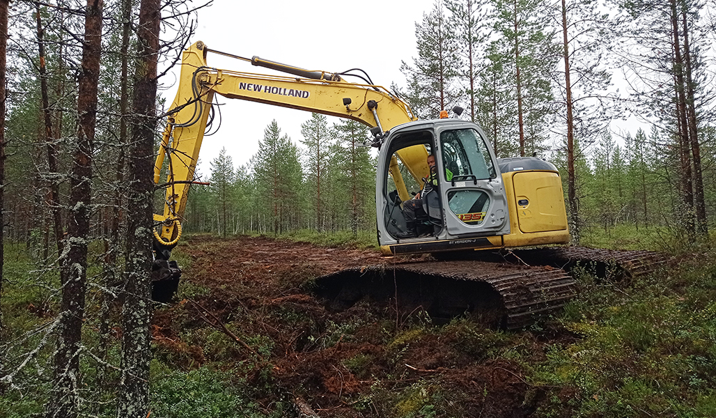 Grävmaskinen håller på att täppa till diket i en myrskog.