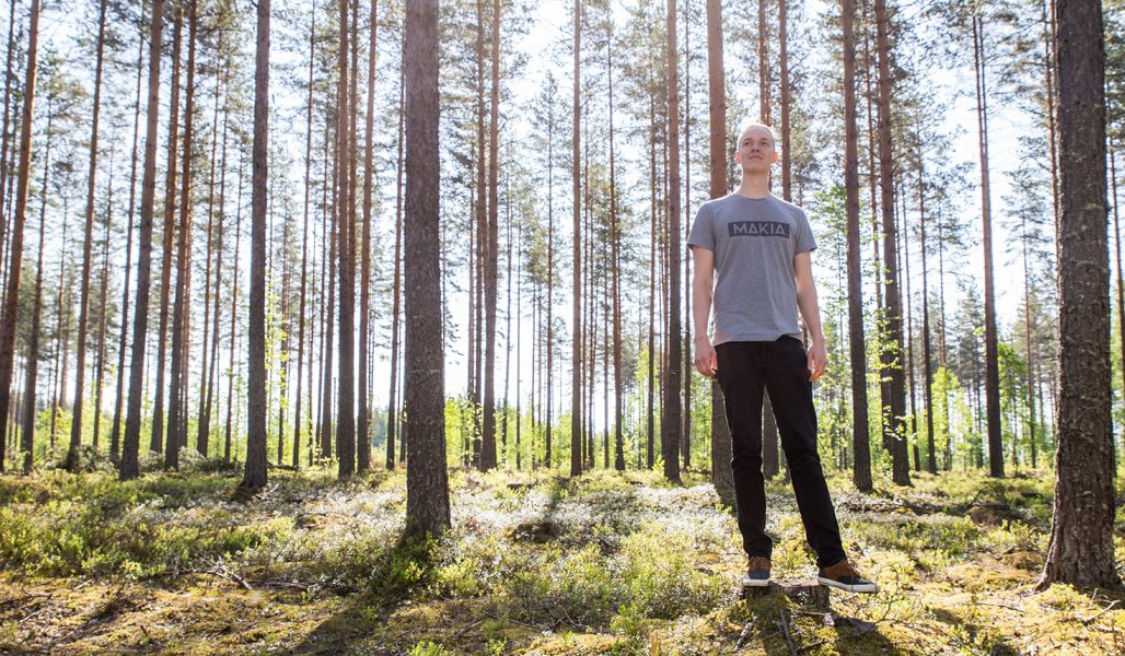 Miikka Kotilainen har fotats i en ekonomiskog bestående till stor del av tall.