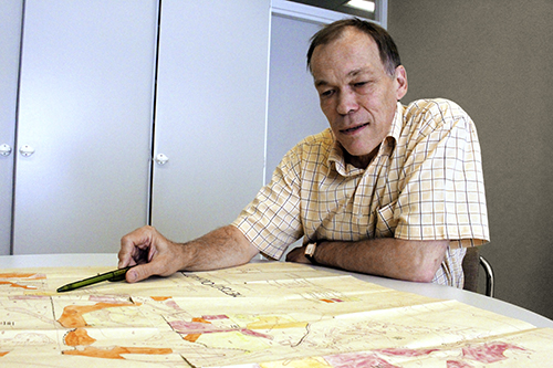 Skogscentralens skogsdatachef Raito Paa­nanen pekar med pennan på en karta han har utbredd framför sig på bordet.