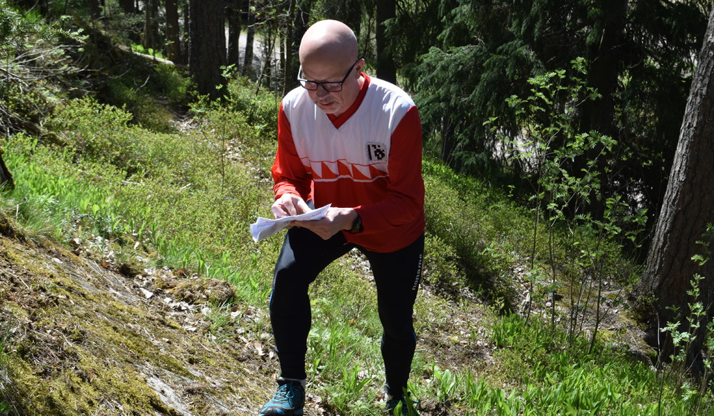 Jyrki Ahvonen står i skogen och tittar på kartan.