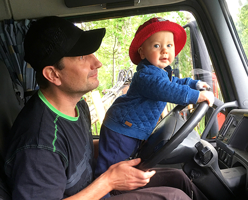 Timo Pesonens ettåriga son Aari styr skogsmaskinen i pappas famn.