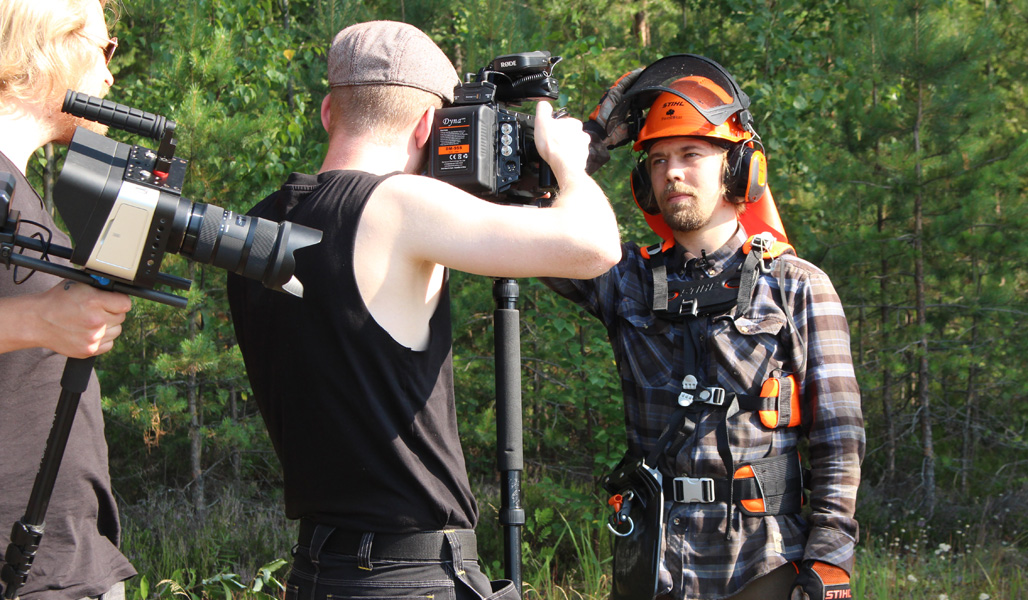 Ett tv-team filmar en skogsklädd Roope Tonteri i skogen.