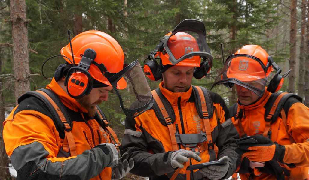 Metsurit Pekka Niskanen, Janne Iivanainen ja Pekka Heikkonen selaavat vierekkäin älypuhelimiaan. 